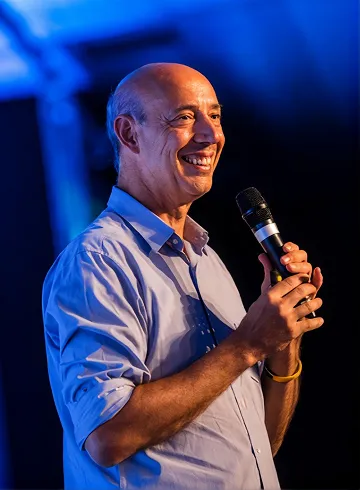 Beto Pandiani sorrindo ao microfone durante uma palestra